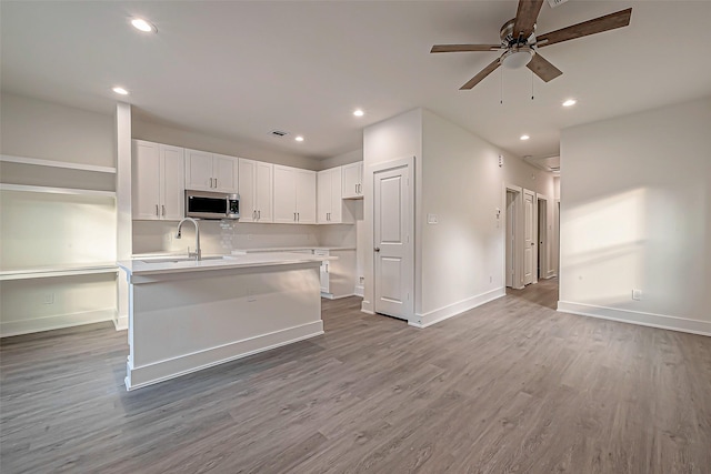 kitchen featuring sink, ceiling fan, an island with sink, light hardwood / wood-style floors, and white cabinetry