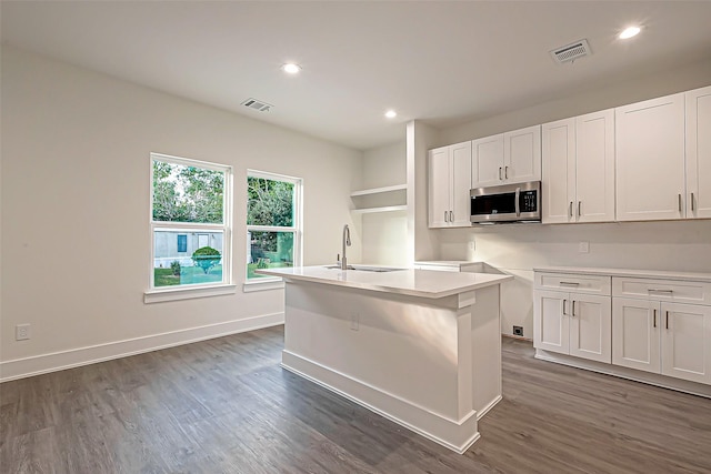 kitchen with white cabinets, a center island with sink, dark hardwood / wood-style floors, and sink