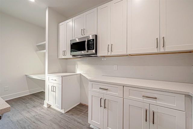 kitchen featuring white cabinets, tasteful backsplash, light stone counters, and light hardwood / wood-style floors