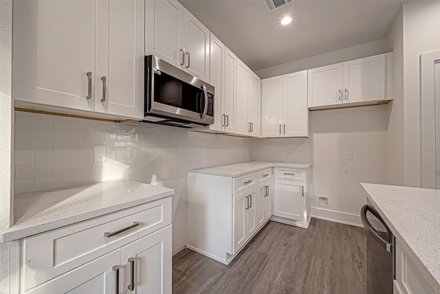 kitchen featuring appliances with stainless steel finishes, light wood-type flooring, white cabinetry, and light stone counters