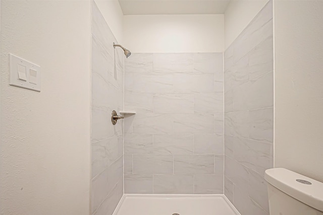 bathroom featuring tiled shower and toilet