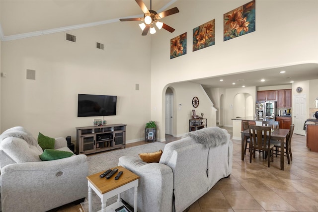 tiled living room featuring ceiling fan, crown molding, and high vaulted ceiling