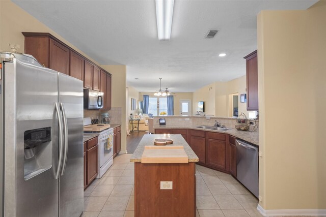 kitchen featuring kitchen peninsula, light tile patterned floors, a center island, and stainless steel appliances