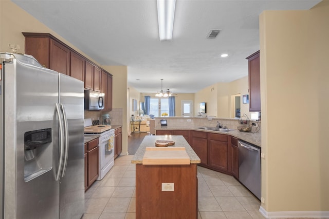 kitchen with stainless steel appliances, a center island, light tile patterned floors, and kitchen peninsula