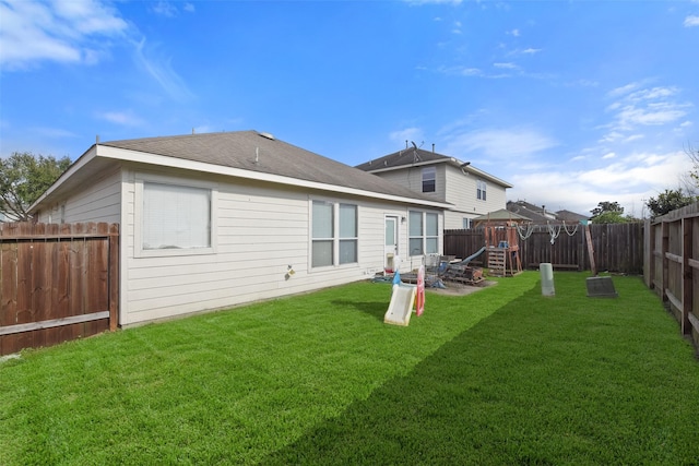 rear view of house featuring a playground and a lawn