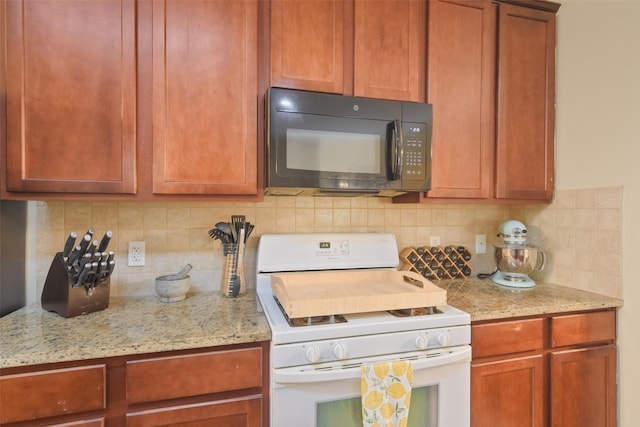 kitchen with backsplash, light stone counters, and white gas stove