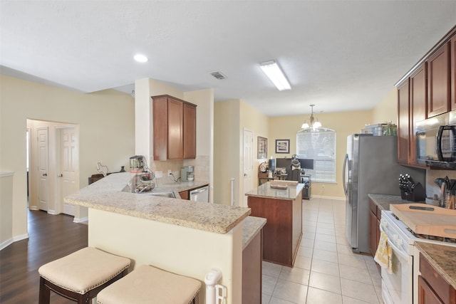 kitchen with sink, hanging light fixtures, a kitchen bar, kitchen peninsula, and white gas stove