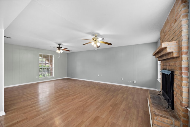 unfurnished living room featuring ceiling fan, a fireplace, and wood-type flooring