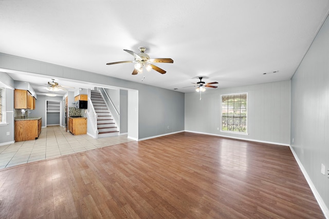 unfurnished living room with ceiling fan, sink, and light hardwood / wood-style floors