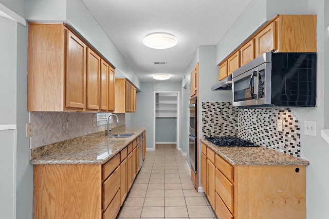 kitchen featuring stainless steel appliances, light tile patterned flooring, sink, and light stone counters