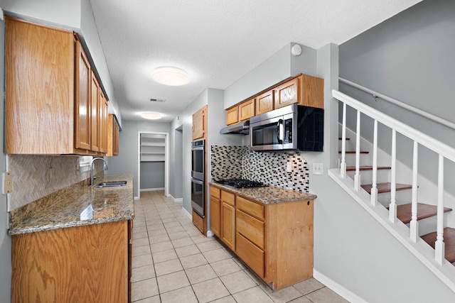 kitchen featuring light stone counters, stainless steel appliances, sink, and light tile patterned floors