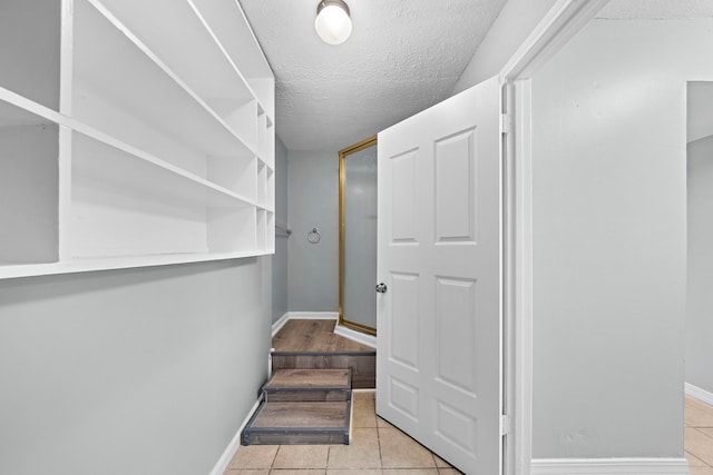 hallway featuring light tile patterned flooring and a textured ceiling