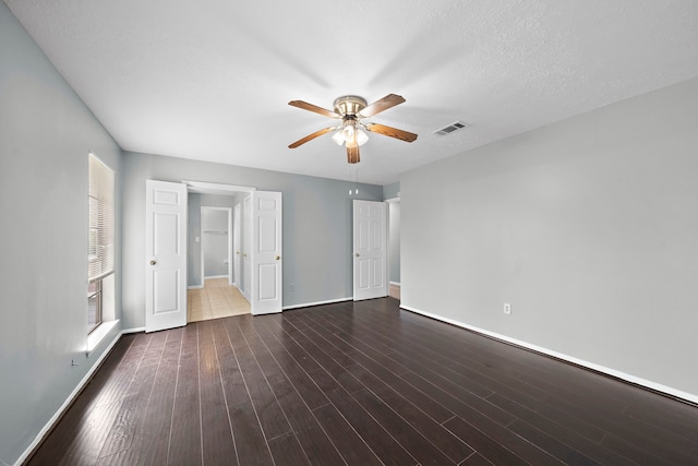 unfurnished bedroom with dark wood-type flooring, ceiling fan, and a textured ceiling