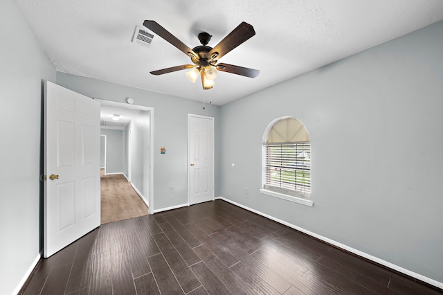 empty room featuring a textured ceiling, dark wood-type flooring, and ceiling fan