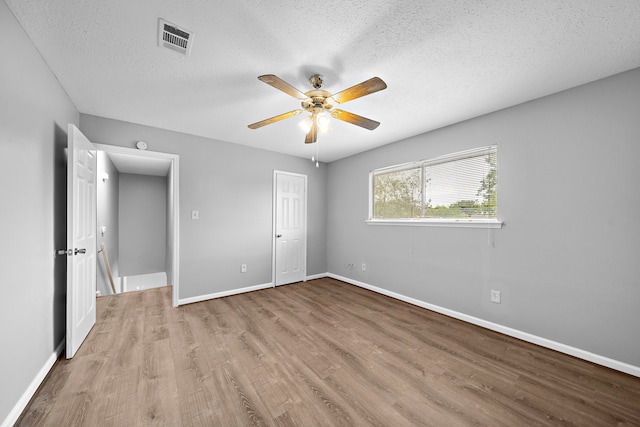 unfurnished bedroom with a closet, ceiling fan, light hardwood / wood-style floors, and a textured ceiling