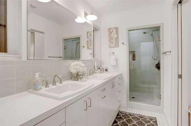 full bath featuring decorative backsplash, double vanity, a stall shower, and a sink