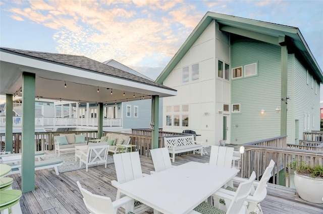 deck at dusk with outdoor lounge area and an outdoor bar