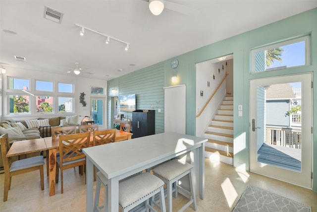 dining room with rail lighting, visible vents, a ceiling fan, and stairs