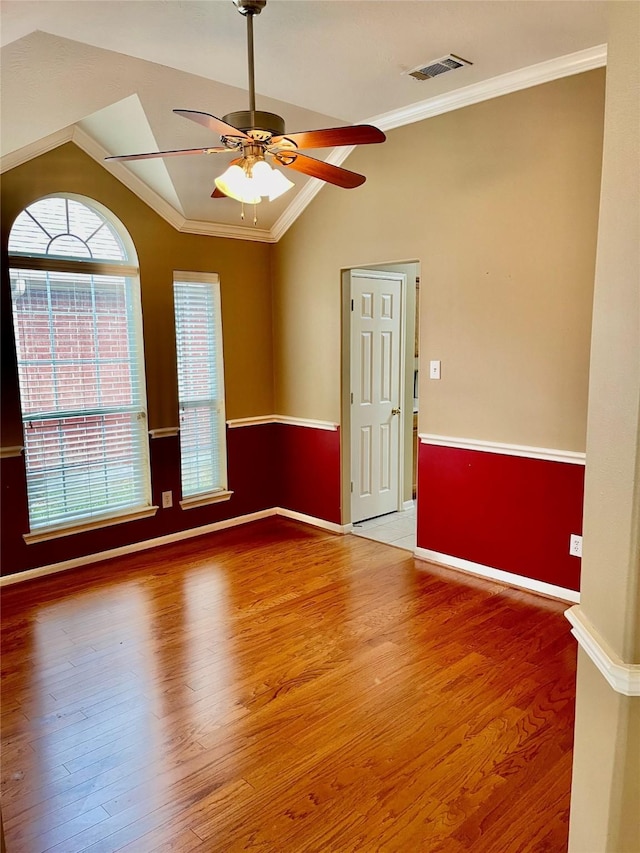 empty room featuring ceiling fan, vaulted ceiling, crown molding, and wood-type flooring