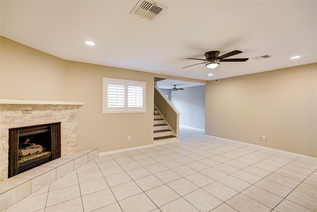 unfurnished living room with ceiling fan, a tile fireplace, and light tile patterned floors