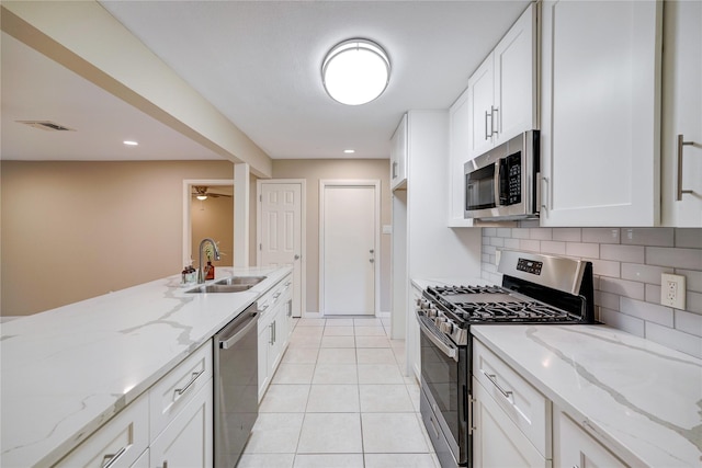 kitchen with sink, stainless steel appliances, light stone countertops, and white cabinetry