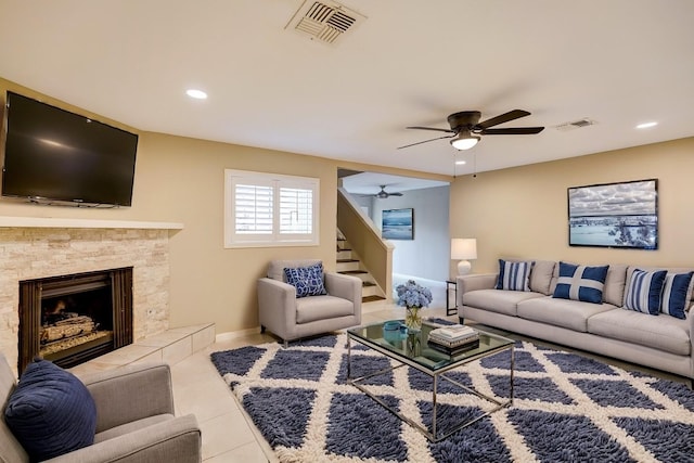 living room with a tile fireplace, ceiling fan, and light tile patterned floors