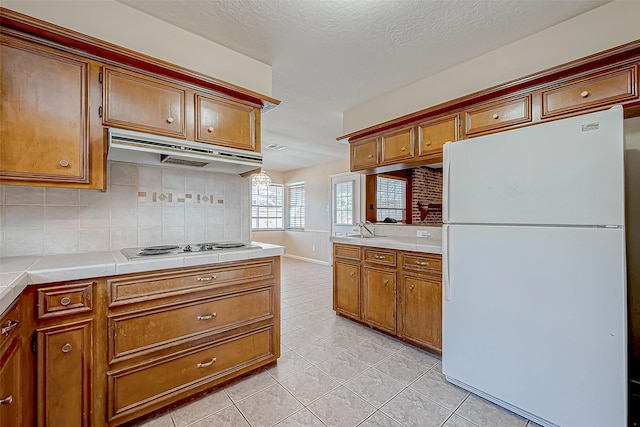 kitchen with sink, tasteful backsplash, tile countertops, white appliances, and light tile patterned floors