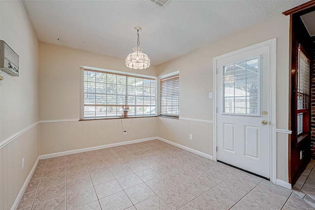 interior space with a wall mounted AC, a textured ceiling, and a notable chandelier