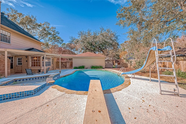 view of swimming pool with a diving board, a water slide, a patio, and an in ground hot tub