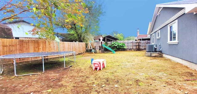 view of yard featuring a playground, cooling unit, and a trampoline