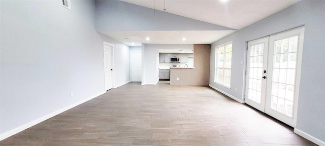 unfurnished living room with french doors, lofted ceiling, and light hardwood / wood-style floors