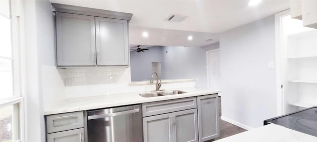 kitchen featuring stainless steel dishwasher, sink, decorative backsplash, and gray cabinetry