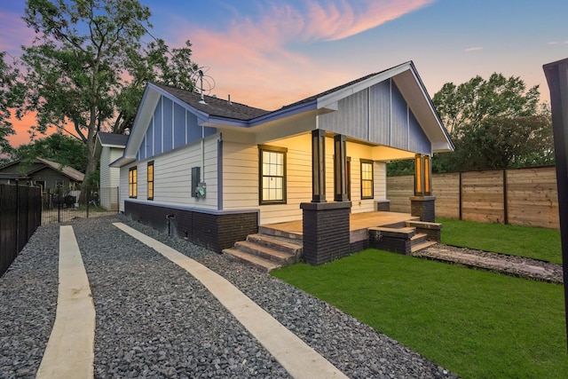 view of front of property with covered porch and a yard