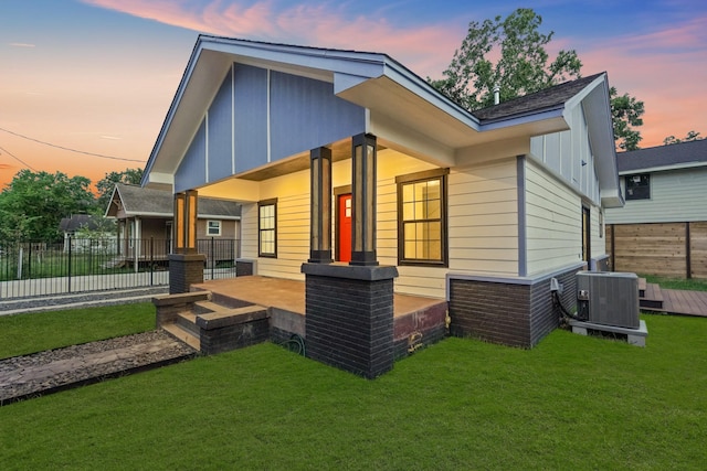 back house at dusk featuring a yard and central AC unit