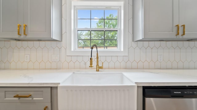 kitchen featuring gray cabinetry, light stone countertops, sink, and stainless steel dishwasher