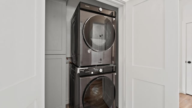 clothes washing area featuring light hardwood / wood-style flooring and stacked washer / dryer