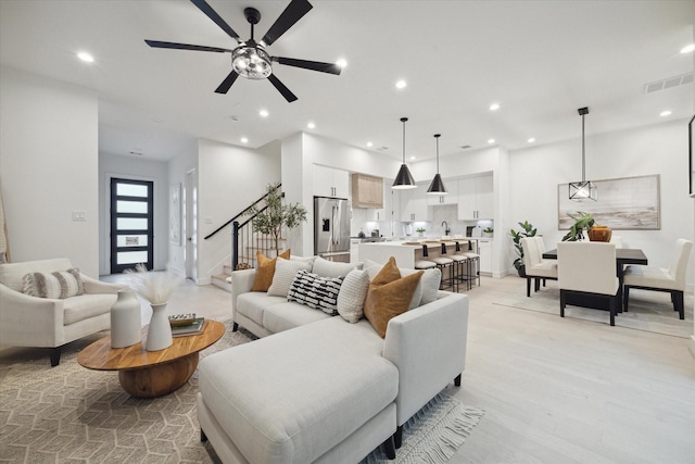 living room with light hardwood / wood-style floors, sink, and ceiling fan