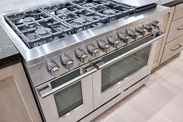 details featuring light brown cabinetry and range with two ovens