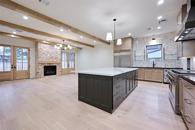 kitchen with french doors, premium appliances, beamed ceiling, and a center island