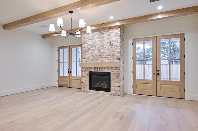 unfurnished living room with french doors, a brick fireplace, and light hardwood / wood-style flooring