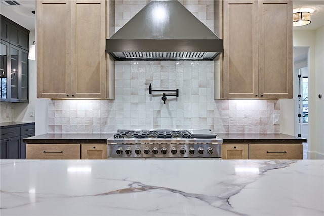 kitchen featuring stainless steel gas cooktop, wall chimney exhaust hood, tasteful backsplash, and light stone countertops