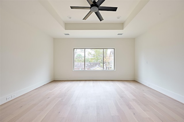 unfurnished room featuring light hardwood / wood-style floors and a raised ceiling