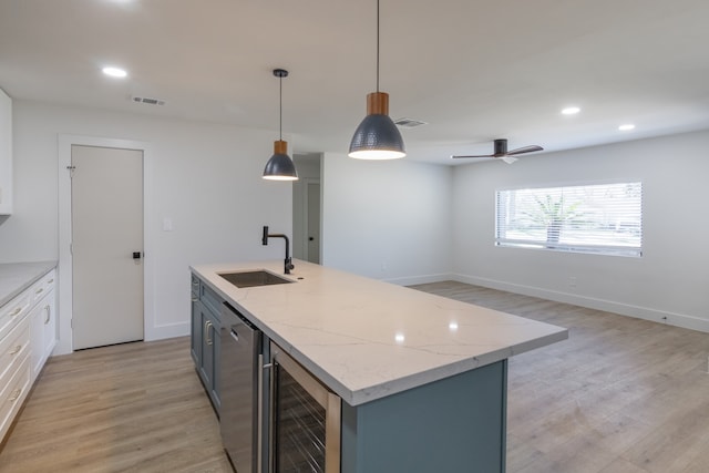 kitchen with sink, white cabinetry, hanging light fixtures, a center island with sink, and beverage cooler