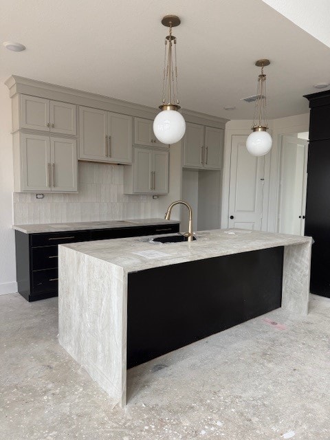 kitchen with decorative light fixtures, gray cabinets, sink, and an island with sink