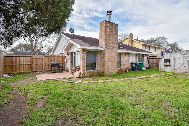 rear view of property featuring a lawn, a patio, a fenced backyard, a chimney, and an outdoor structure