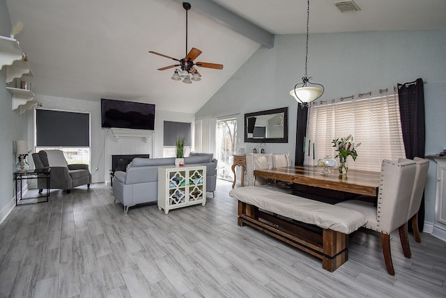 dining area with wood finished floors, beam ceiling, a glass covered fireplace, and visible vents