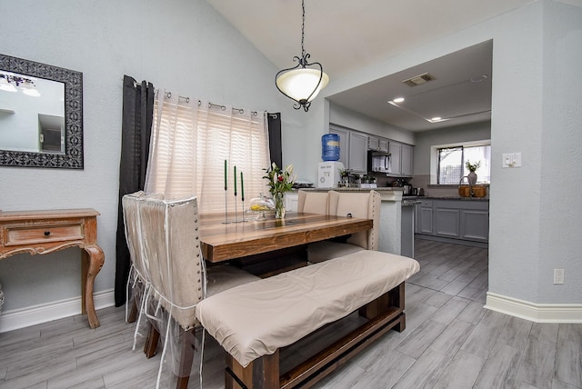 dining space featuring vaulted ceiling, baseboards, visible vents, and wood tiled floor