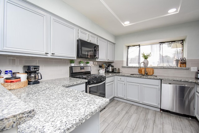 kitchen featuring tasteful backsplash, recessed lighting, appliances with stainless steel finishes, a sink, and light wood-type flooring