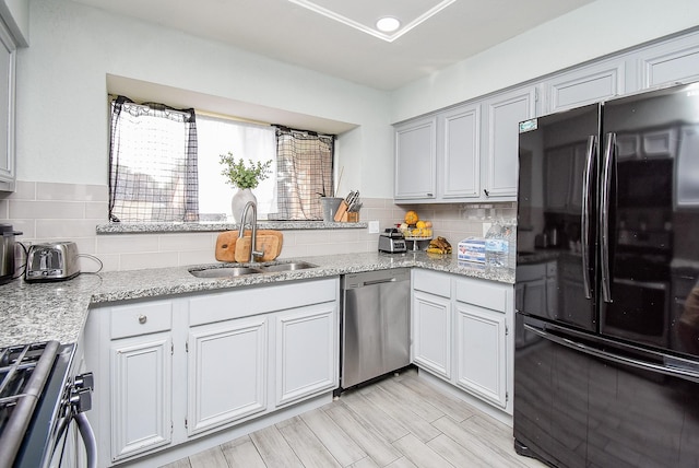 kitchen featuring stainless steel appliances, light stone counters, a sink, and decorative backsplash