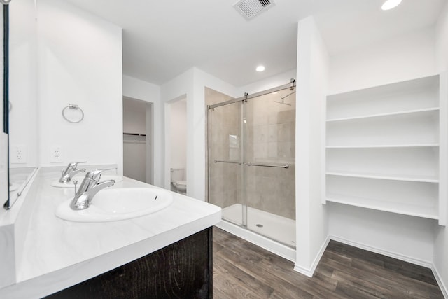 bathroom with an enclosed shower, vanity, hardwood / wood-style flooring, and toilet